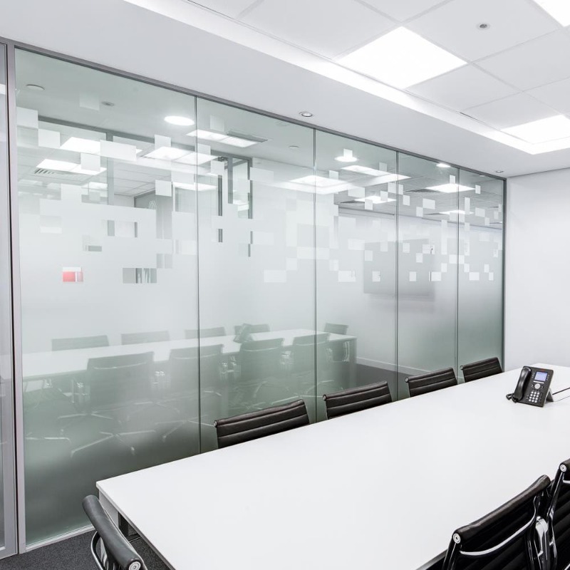 Fixed glass office partition dividing an open workspace