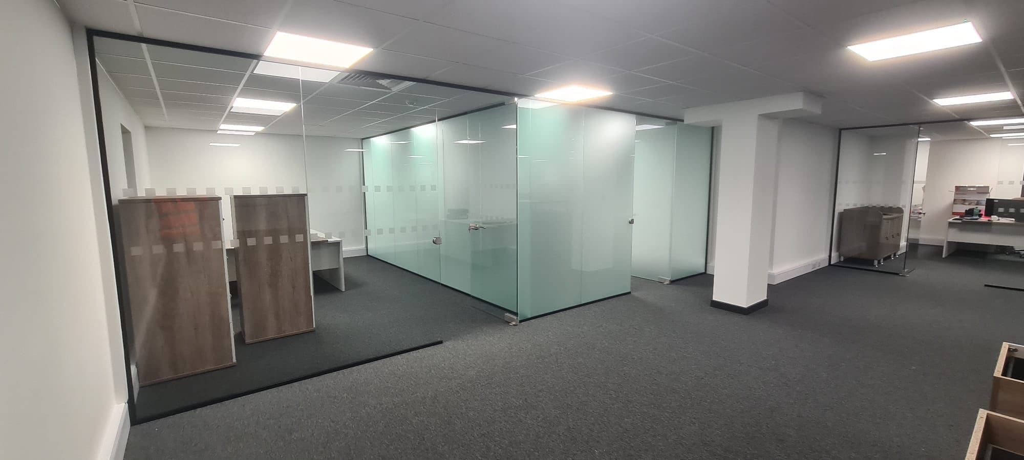 T-shaped glass partition with black channels, glass door and returning divider