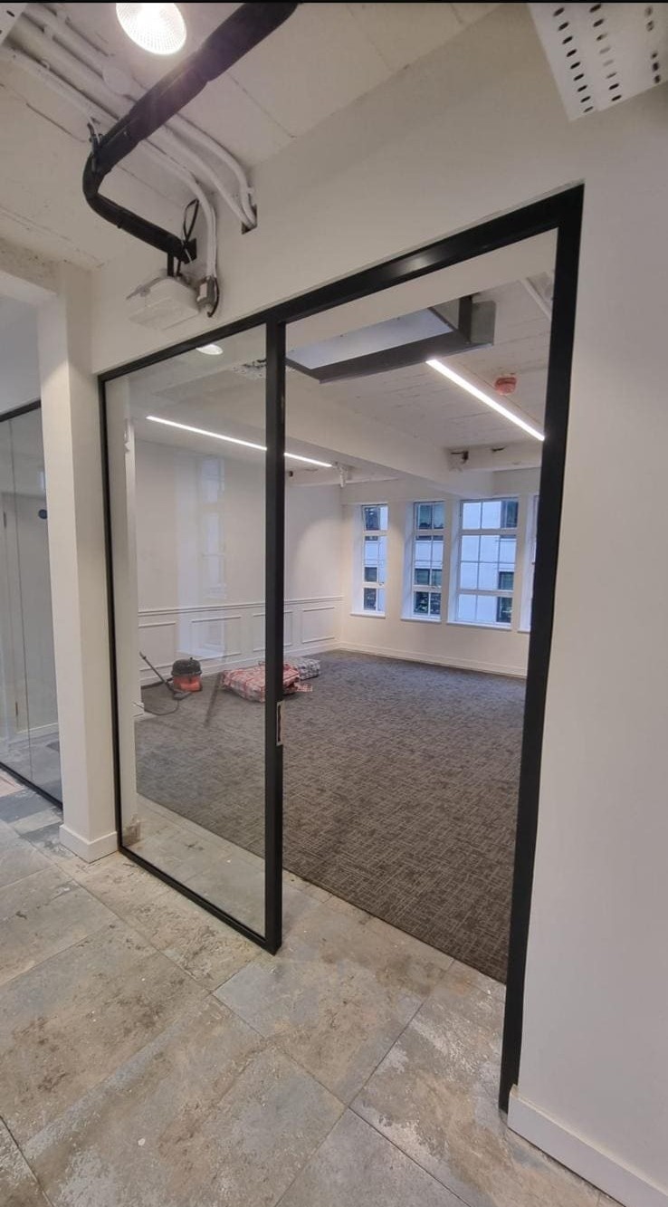 Completed glass partition installed beneath a bulkhead built around overhead services