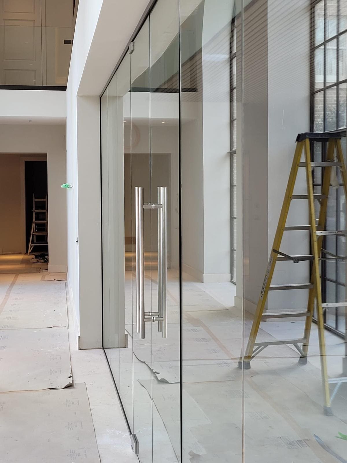 Frameless glass partition installation in progress with access equipment still on site