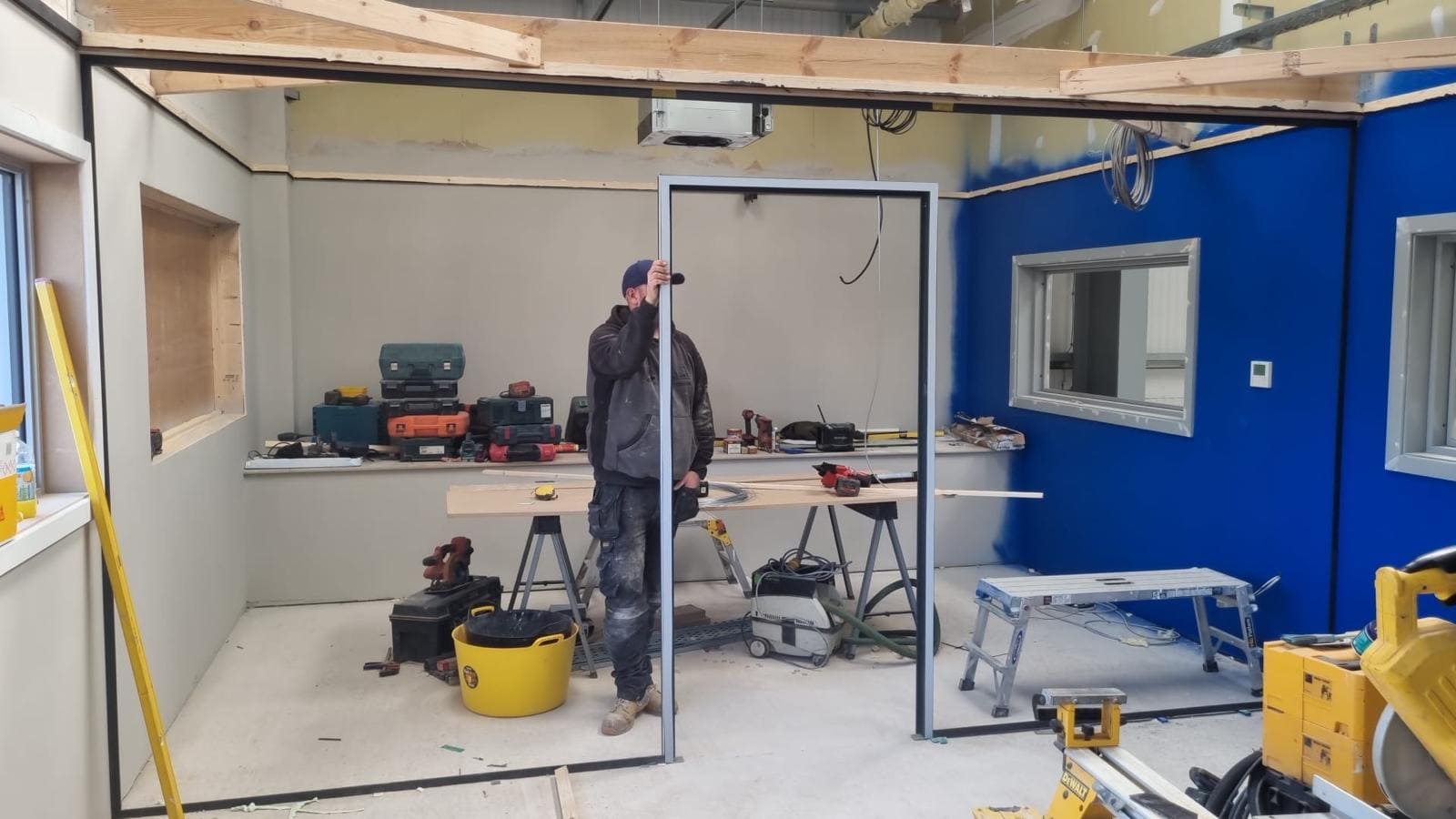 Installer fitting a silver framed glass door during an active building project
