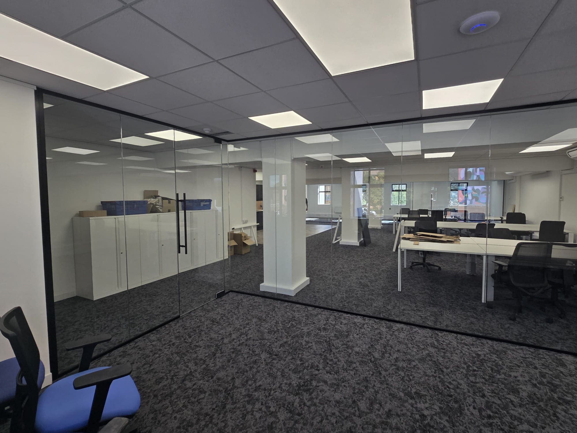 Black aluminium profiles installed around a frameless office glass partition