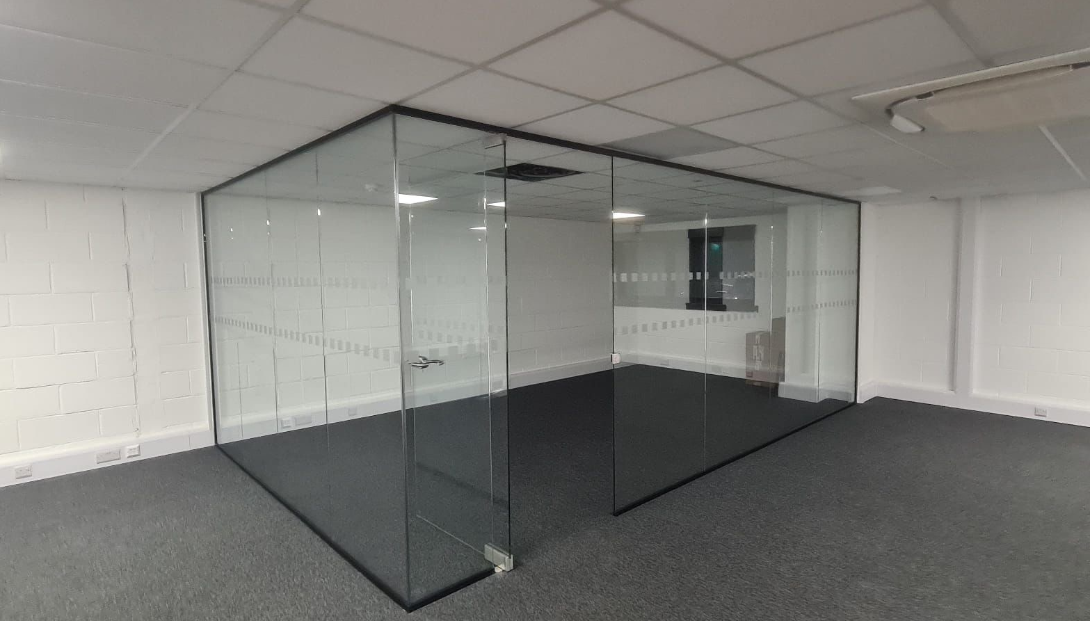Black channel corner glass partition creating an office meeting room