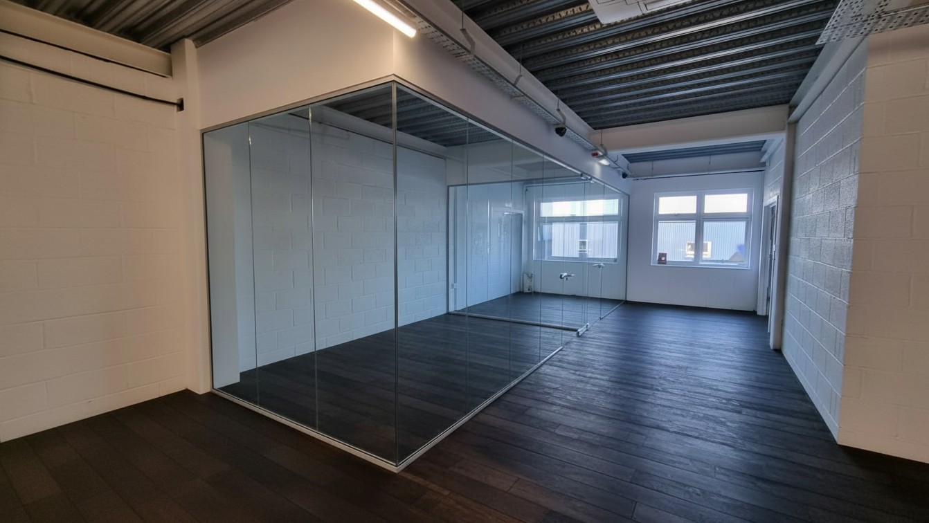 Silver channel corner glass partition dividing a workplace into private offices